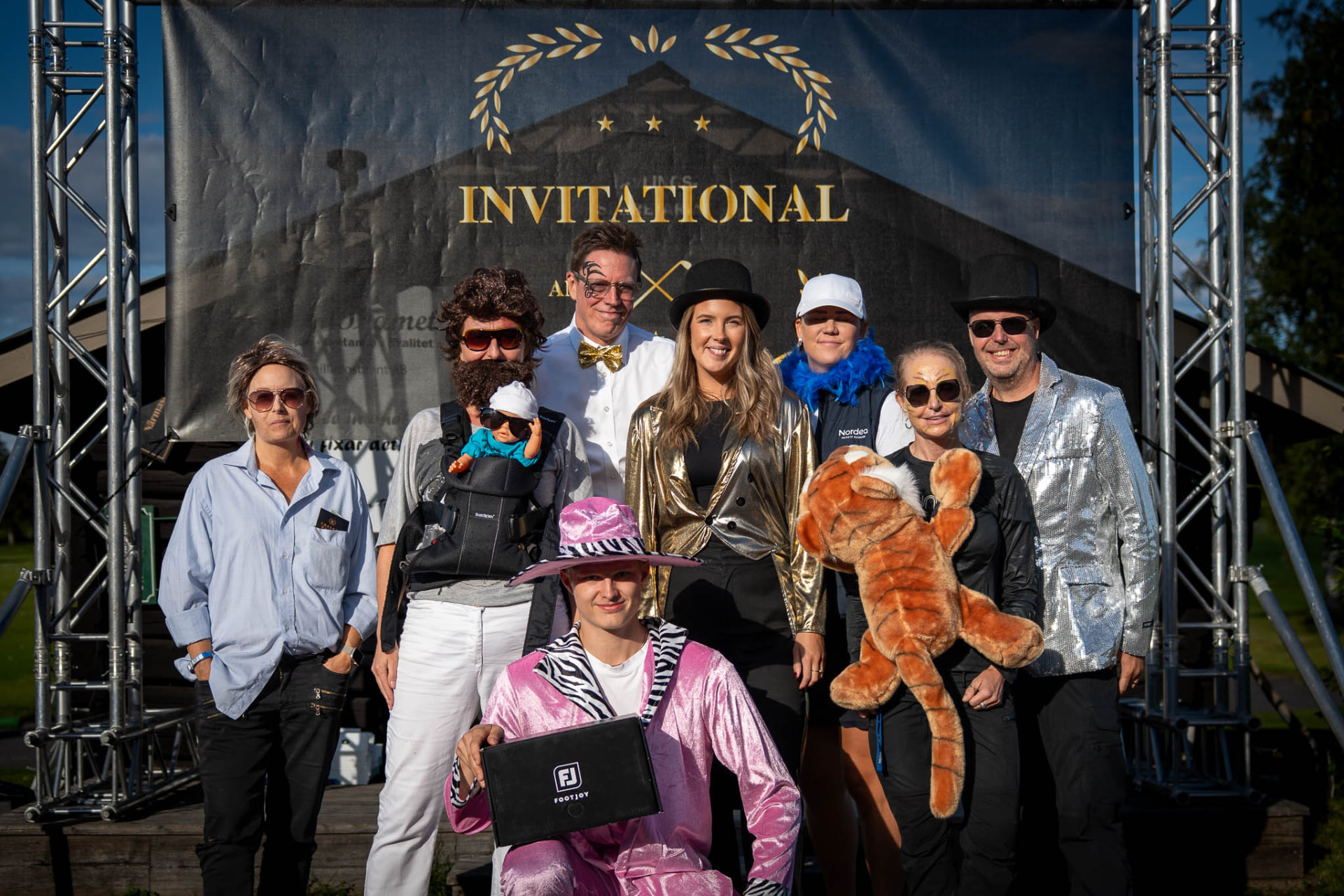 Deltagare i utklädnad framför Tell Invitational-backdropen